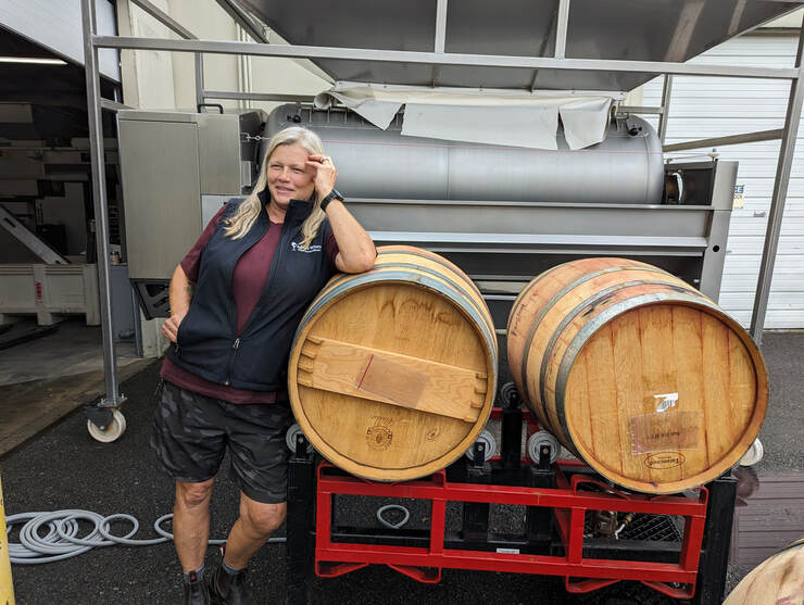 Pam Adkins in front of wine barrels